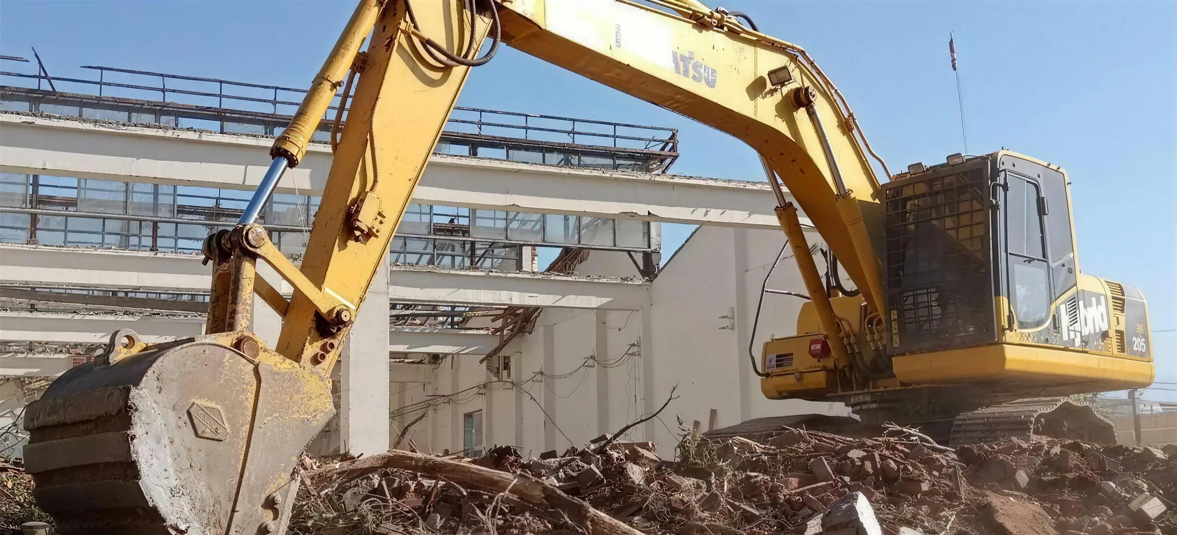 Excavadora demoliendo la estructura de una fábrica